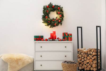 Christmas decor on cabinet and firewood near white wall indoors. Interior designの写真素材