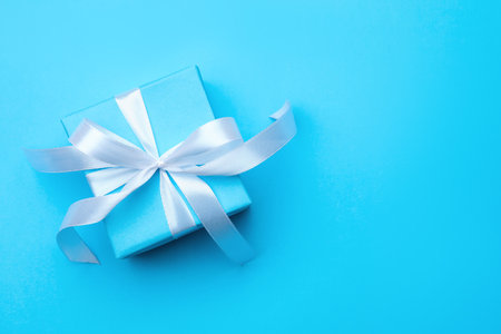One gift box with ribbon on light blue background, top view. Space for textの写真素材