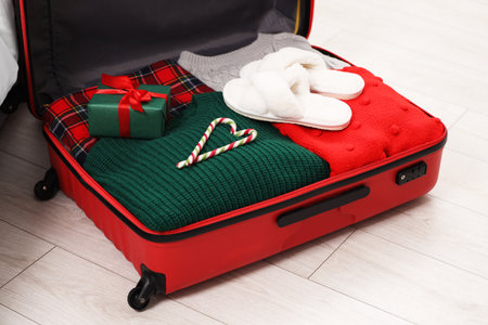 Suitcase with clothes, candy canes and gift box on floor indoors, closeupの写真素材