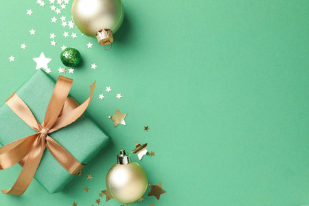 Beautiful Christmas composition with gift and decor on green background, flat lay. Space for text