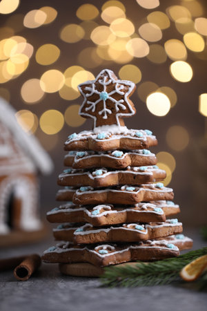 Christmas tree made of gingerbread cookies, cinnamon, dried orange slice and fir branch on gray table against blurred lights, closeupの写真素材