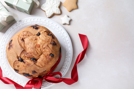 Tasty Christmas panettone cake, gingerbread cookies and gifts on beige table, flat lay. Space for...