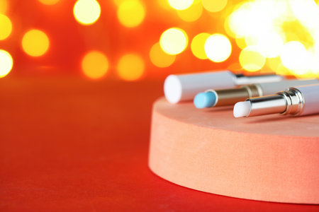 Lip balms on red background against blurred lights, closeup with space for text. Christmas presentの写真素材