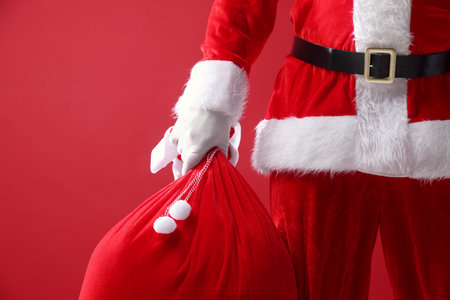 Santa Claus holding sack on red background, closeup with space for text. Merry Christmas and Happy New Yearの写真素材