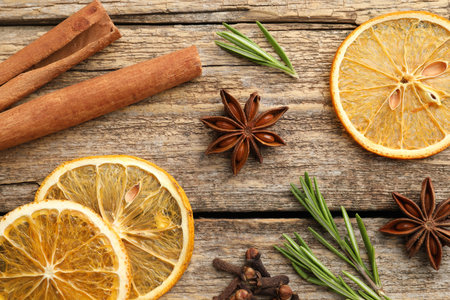 Different spices, dry orange slices and fresh rosemary for mulled wine on wooden table, flat layの写真素材