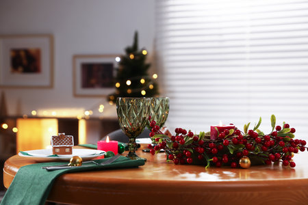 Christmas table setting with plates, glasses and burning candles in festive decorated roomの写真素材