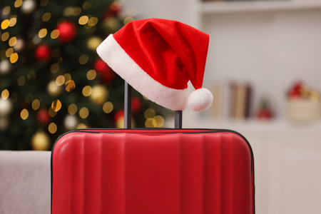 Christmas vacation. Suitcase with Santa hat and gift box indoors, closeupの写真素材