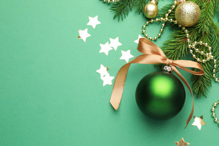 Beautiful Christmas composition with baubles, fir branches and confetti on green background, flat lay. Space for textの写真素材