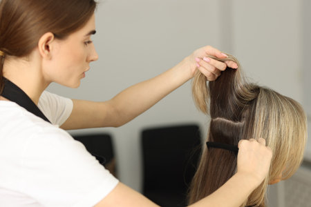 Hairdresser combing woman's hair in beauty salon