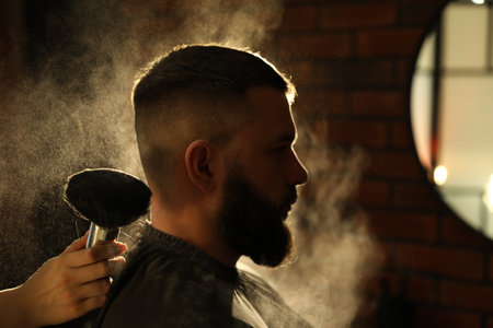 Hairstylist applying talcum powder with brush onto man's neck at salon, closeupの写真素材