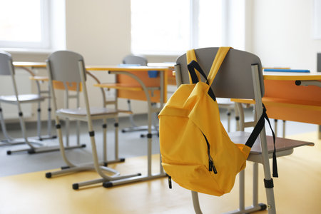 Chair with backpack near desk in classroom at school, selective focusの写真素材