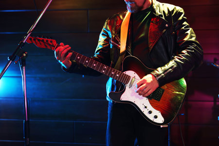 Man with electric guitar on stage, closeupの写真素材