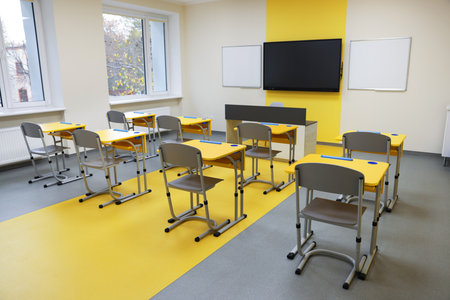 Stylish classroom with desks, chairs and TV at schoolの写真素材