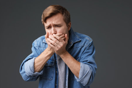 Young man suffering from nausea on gray backgroundの写真素材