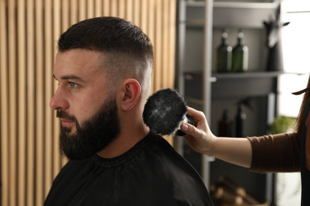 Hairstylist applying talcum powder with brush onto man's hair at salon, closeupの写真素材