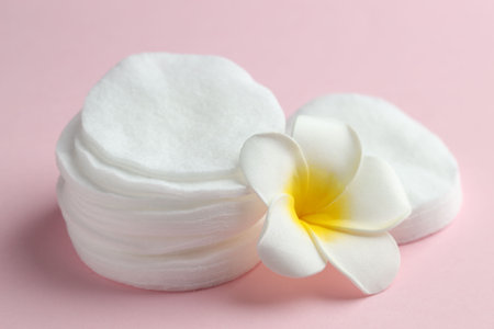 Clean cotton pads and plumeria flower on pink background, closeupの写真素材