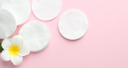 Clean cotton pads and plumeria flower on pink background, flat lay. Space for textの写真素材