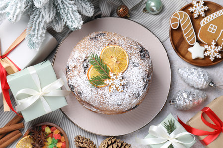 Tasty panettone cake, spices, candied fruits and Christmas decor on gray table, flat layの写真素材