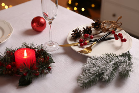 Festive table setting with Christmas decor and burning candle indoors, closeupの写真素材