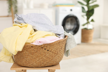 Laundry basket with clothes on wooden table indoors, closeup. Space for textの写真素材