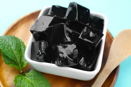 Tasty herbal jelly in bowl and mint on light blue background, closeupの写真素材