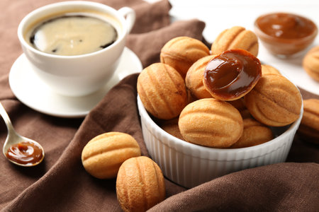 Delicious nut shaped cookies with boiled condensed milk served with coffee on white table, closeupの写真素材