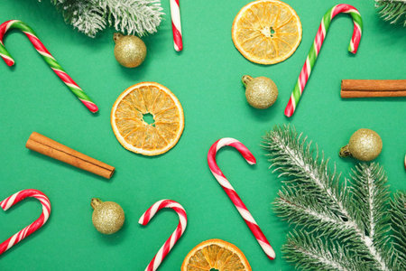 Christmas celebration. Candy canes, spices and festive decor on green background, flat layの写真素材