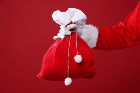 Santa Claus holding sack on red background, closeup with space for text. Merry Christmas and Happy New Yearの写真素材