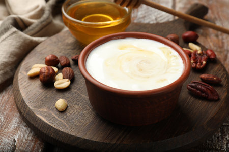 Delicious Greek yogurt with honey and nuts served on wooden table, closeupの写真素材