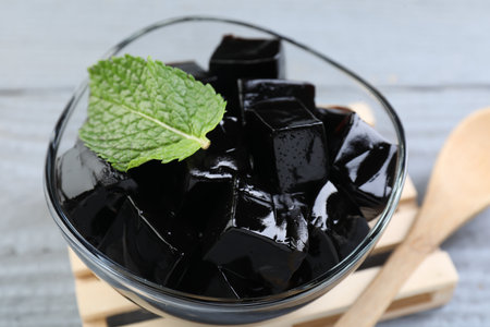Tasty herbal jelly in glass bowl and mint on gray wooden table, closeupの写真素材