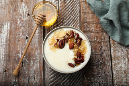 Delicious Greek yogurt with honey and nuts served on wooden table, flat layの写真素材