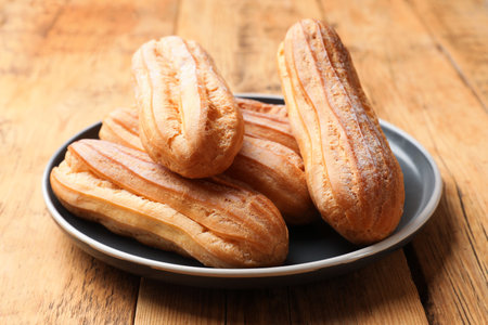Delicious golden eclairs on wooden table, closeupの写真素材