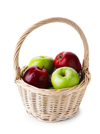 Red and green ripe apples in wicker basket isolated on whiteの写真素材