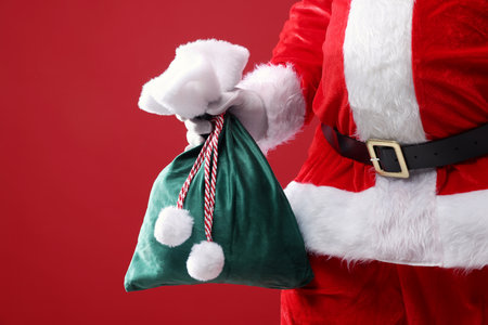 Santa Claus holding sack on red background, closeup. Merry Christmas and Happy New Yearの写真素材