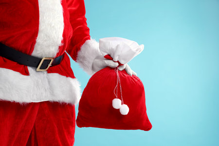 Santa Claus holding sack on light blue background, closeup with space for text. Merry Christmas and Happy New Yearの写真素材