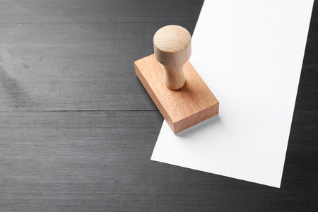 One wooden stamp and blank sheet of paper on black table. Space for textの写真素材