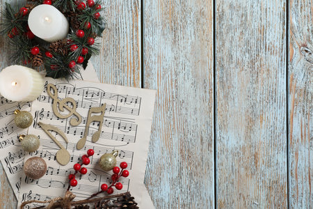 Golden music notes, sheets and Christmas decor on wooden table, flat lay. Space for textの写真素材