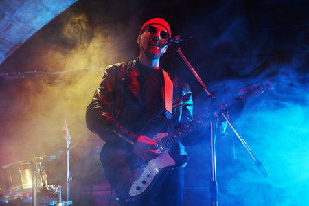 Man playing electric guitar on stage with smoke, low angle viewの写真素材