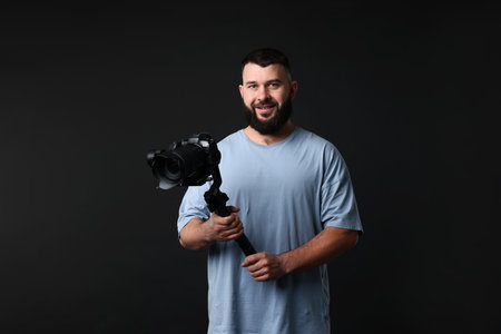 Videographer using gimbal stabilizer with camera on black backgroundの写真素材