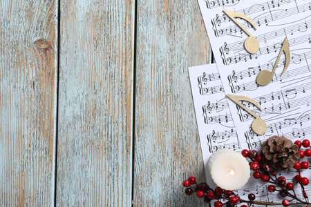 Golden music notes, sheets and Christmas decor on wooden table, flat lay. Space for textの写真素材
