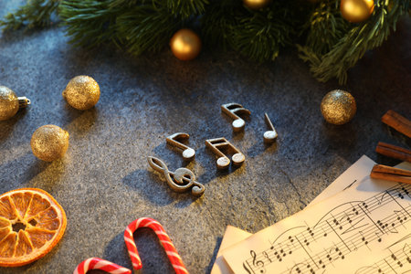 Golden music notes, sheets, Christmas decor and treats on gray textured table, closeupの写真素材