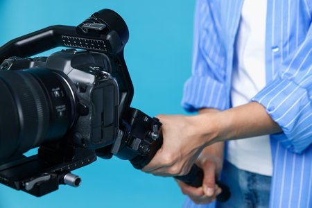 Videographer using gimbal stabilizer with camera on light blue background, closeupの写真素材