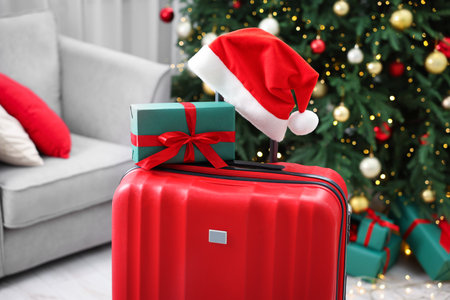 Christmas vacation. Suitcase with Santa hat and gift box indoors, closeupの写真素材