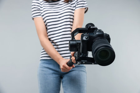 Videographer using gimbal stabilizer with camera on light background, closeupの写真素材