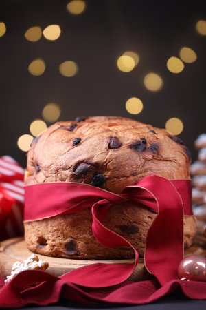 Christmas food. Delicious Panettone cake, gingerbread cookie and decor on table against blurred lights, closeup. Bokeh effectの写真素材