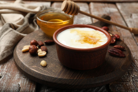 Delicious Greek yogurt with honey and nuts served on wooden table, closeupの写真素材