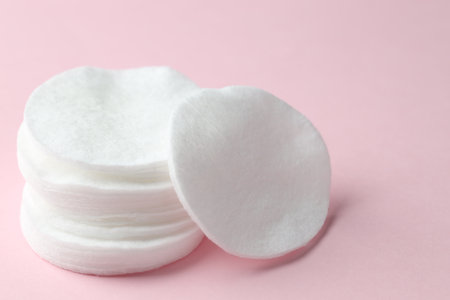 Stack of clean cotton pads on pink background, closeup. Space for textの写真素材