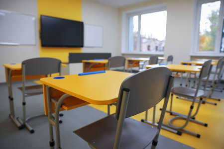 Stylish classroom with desks, chairs and TV at school, selective focusの写真素材