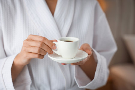 Woman in bathrobe with morning coffee indoors, closeupの写真素材