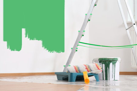 Decorator's stuff in room. Wall partly painted in green color. Interior renovationの写真素材